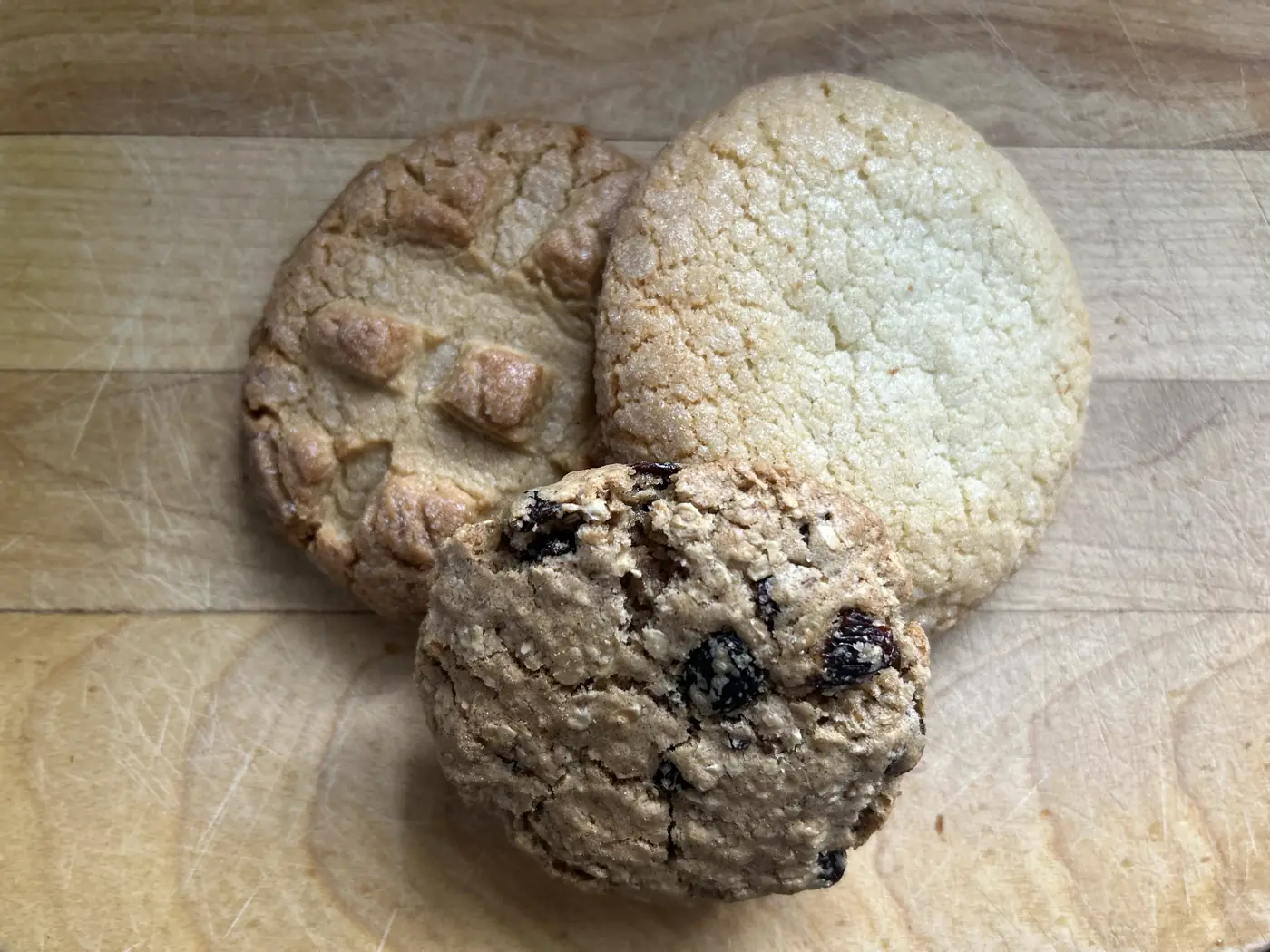 Three cookies on a wooden board seen from above